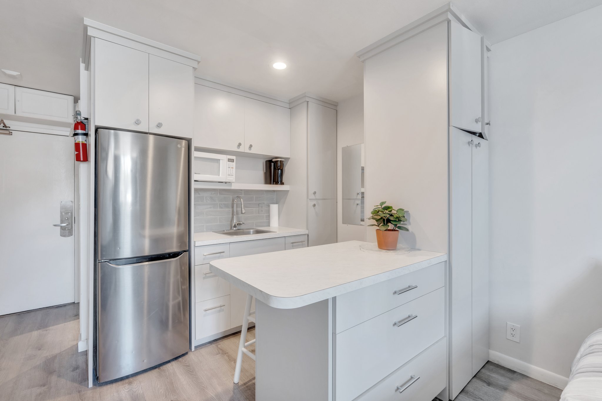 Kitchen with open shelves, a sink, freestanding refrigerator, light wood-type flooring, and white microwave
