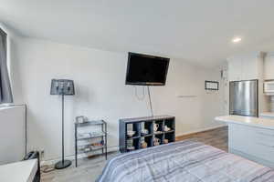 Bedroom featuring recessed lighting, baseboards, light wood-style floors, and freestanding refrigerator