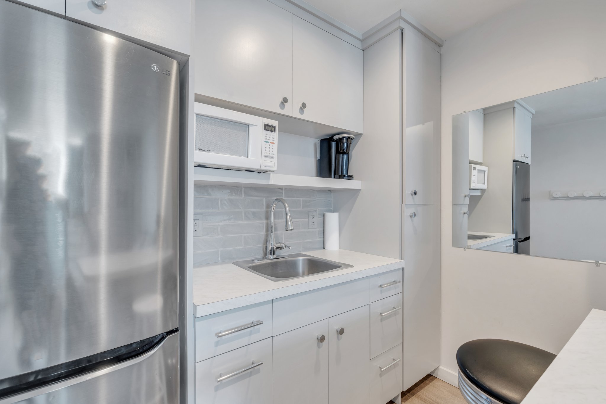 Kitchen featuring light countertops, a sink, white microwave, and freestanding refrigerator