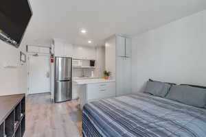 Bedroom with recessed lighting, light wood-style flooring, a sink, and freestanding refrigerator
