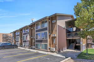 View of property with uncovered parking and stairs