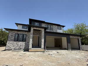 View of front of home featuring stone siding and an attached garage