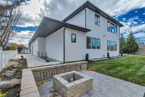 Rear view of property featuring stucco siding, an outdoor fire pit, and a patio area