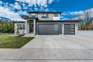 Prairie-style home featuring stone siding, driveway, and an attached garage