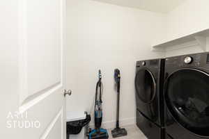 Clothes washing area with light wood-style flooring, baseboards, washer and clothes dryer, and laundry area