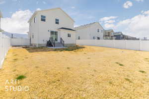 Rear view of house featuring a fenced backyard, stucco siding, and a lawn