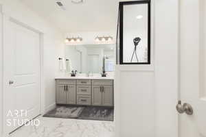 Bathroom with visible vents, marble finish floor, a sink, and double vanity