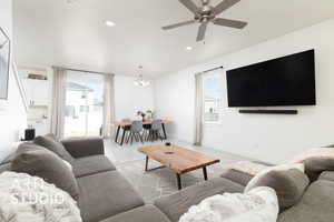 Living area featuring baseboards, recessed lighting, ceiling fan with notable chandelier, and light wood-style flooring