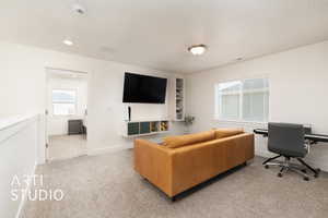 Living area with carpet, visible vents, and baseboards