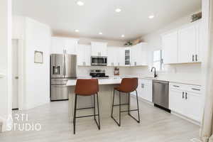 Kitchen with stainless steel appliances, a sink, a kitchen bar, light wood-style floors, and a kitchen island