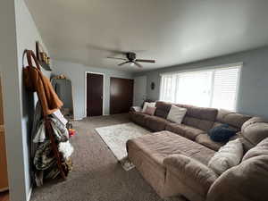 Carpeted living area featuring ceiling fan