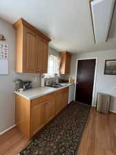 Kitchen with a sink, light wood-style floors, dishwasher, light countertops, and baseboards