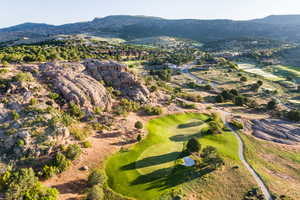 Aerial view of property and surrounding area featuring a mountainous background and a golf course