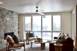 Living room with built in shelves, recessed lighting, a stone fireplace, healthy amount of natural light, and a ceiling fan