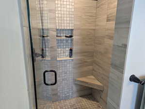 A custom large tile shower with seat, in wall shelves, and frameless glass.