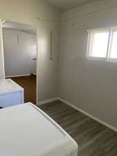 Unfurnished bedroom with baseboards, wood finished floors, and washer and dryer