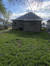 Back of property with a lawn, central AC, fence, and a shingled roof