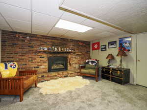 Living room featuring a paneled ceiling, a brick fireplace, and carpet floors