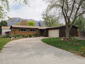 Ranch-style house with a mountain view, driveway, a garage, brick siding, and a front yard