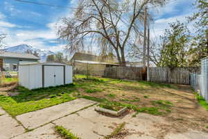 View of yard featuring a storage shed, a mountain view, fence, and an outdoor structure