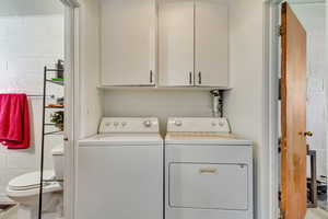 Washroom with cabinet space, concrete block wall, and washer and clothes dryer