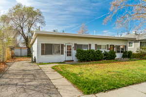 View of front facade featuring fence, a front lawn, aphalt driveway, and concrete block siding