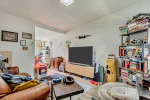 Living area with lofted ceiling, concrete block wall, and wood finished floors