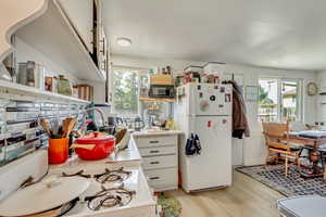 Kitchen with plenty of natural light, light wood-style flooring, white appliances, and light countertops