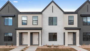 Townhome / multi-family property with brick siding, roof with shingles, and stucco siding