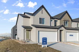 View of front facade featuring concrete driveway, a front yard, and a garage