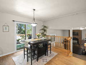 Dining space with baseboards, a brick fireplace, a textured ceiling, and light wood-style floors