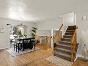 Dining space with baseboards, wood finished floors, a textured ceiling, and stairs
