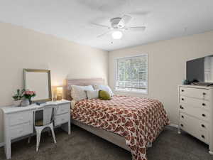 Bedroom featuring a ceiling fan, dark carpet, and a textured ceiling
