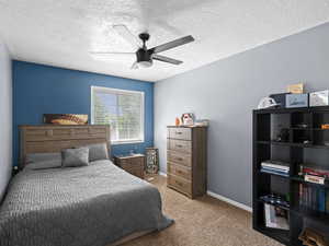 Bedroom featuring baseboards, carpet floors, a textured ceiling, and ceiling fan