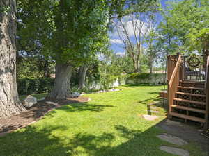 View of yard featuring a wooden deck, a fenced backyard, and stairway