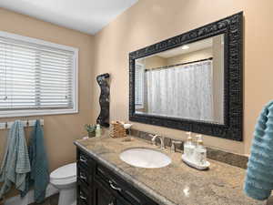 Full bathroom with a shower with shower curtain, toilet, and vanity