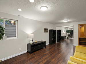 Living area featuring baseboards, wood finished floors, visible vents, and a textured ceiling