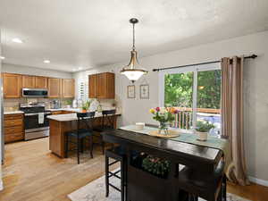 Dining room featuring a textured ceiling, recessed lighting, light wood-style floors, and a healthy amount of sunlight