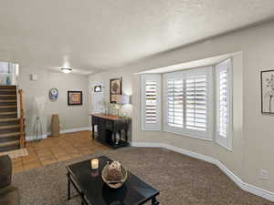 Living area featuring stairway, tile patterned floors, a textured ceiling, and plenty of natural light