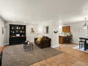 Living room featuring recessed lighting, a textured ceiling, baseboards, and light tile patterned floors