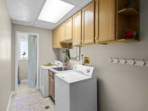 Laundry room with baseboards, light tile patterned flooring, washer / clothes dryer, and cabinet space