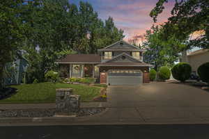 View of front facade with a garage, brick siding, a front yard, and concrete driveway