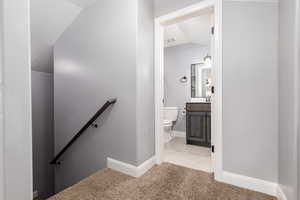 Staircase featuring baseboards, visible vents, lofted ceiling, tile patterned flooring, and carpet floors