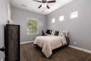 Carpeted bedroom with baseboards, a ceiling fan, and visible vents