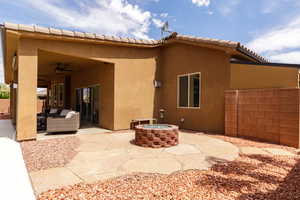 Back of property with stucco siding, a ceiling fan, an outdoor living space with a fire pit, and a patio