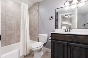Bathroom with shower / bath combination with curtain, toilet, vanity, and baseboards