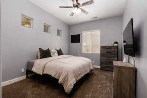 Bedroom featuring dark carpet, visible vents, a ceiling fan, and baseboards