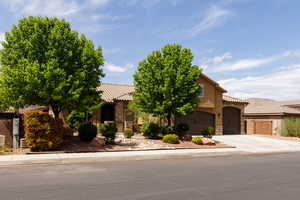 View of front of property with a tile roof, driveway, stone siding, a garage, and stucco siding