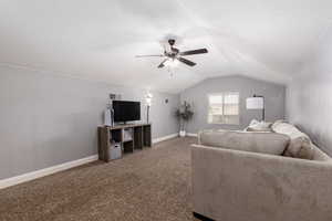 Carpeted living area featuring lofted ceiling, a ceiling fan, visible vents, and baseboards