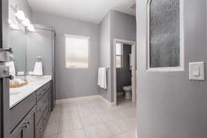 Full bathroom with tile patterned flooring, double vanity, toilet, a sink, and baseboards